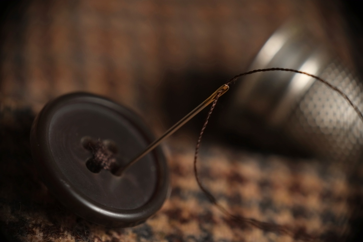 Sewing button on a tweed coat