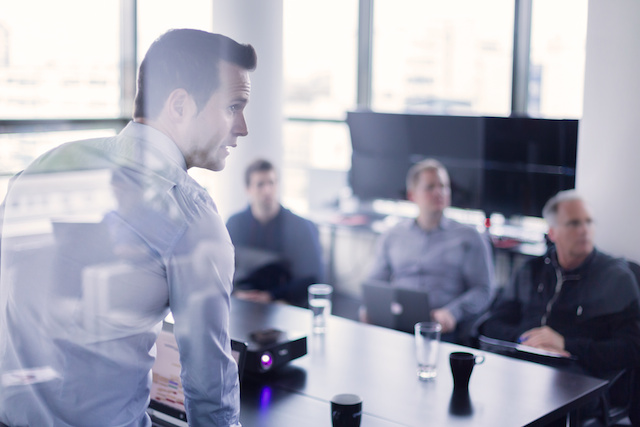 Business man making a presentation at office. Business executive delivering a presentation to his colleagues during meeting or in-house business training, explaining business plans to his employees.