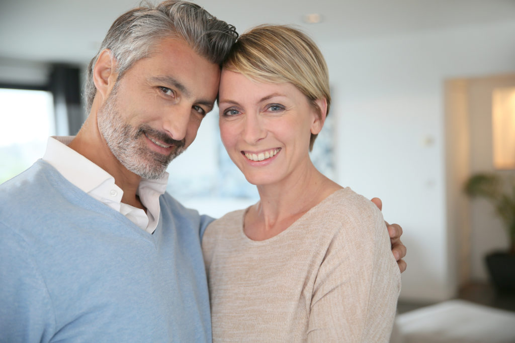 Smiling middle-aged couple standing in brand new home